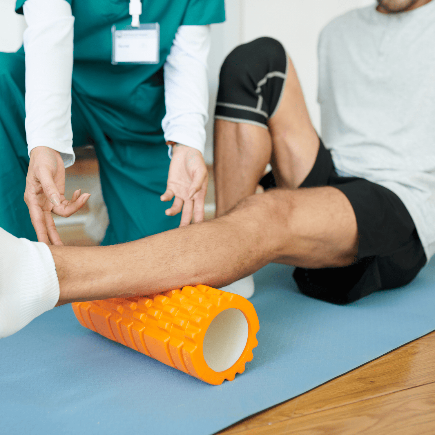 Rehab therapist showing a patient how to use a bright orange foam roller on the patient's calf muscle